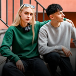 Woman showing how to style a crewneck sweatshirt with a graphic tee and beanie